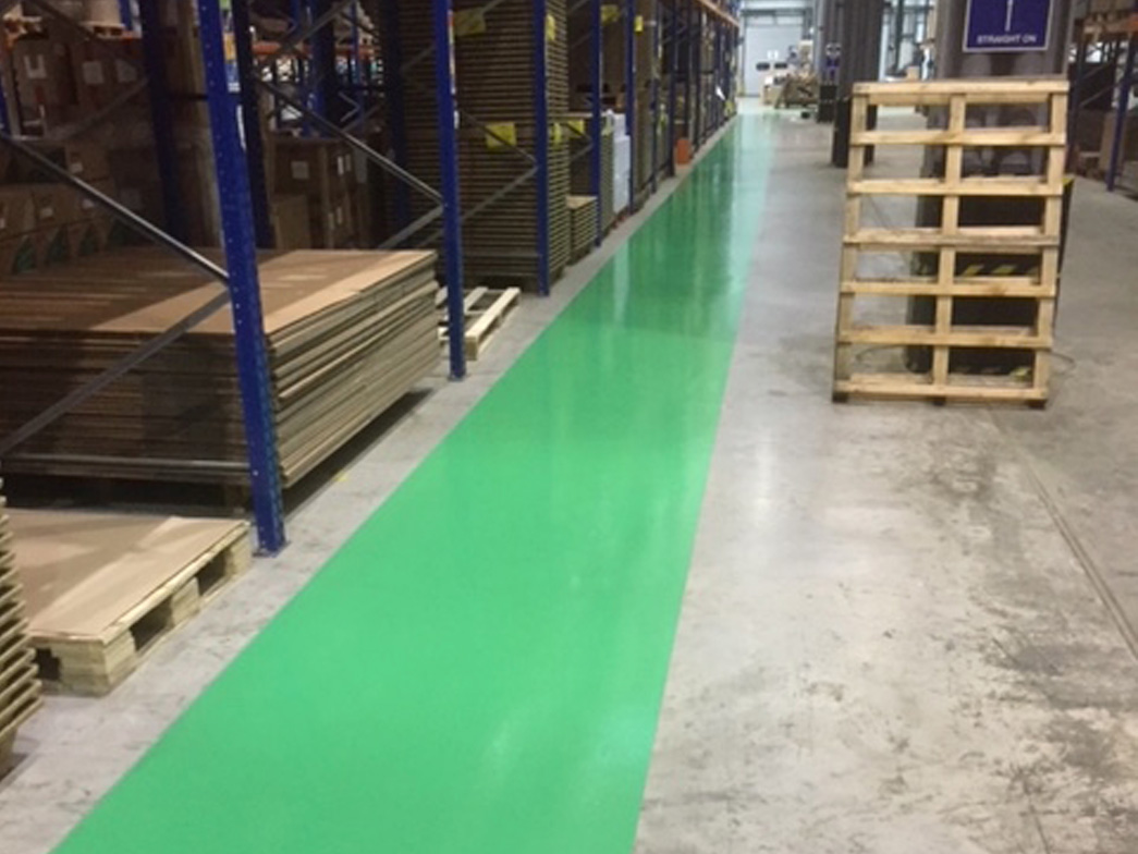 A green walkway painted on factory floor